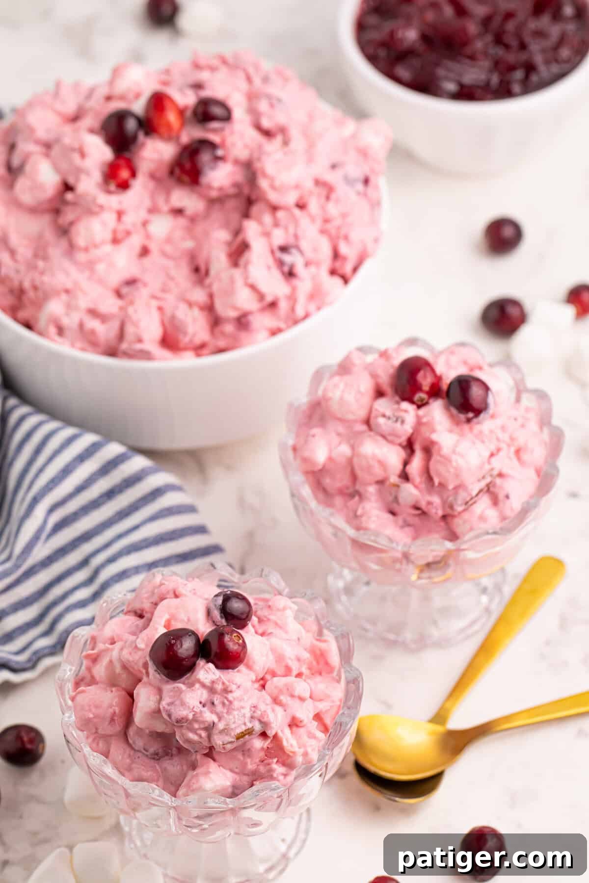 Cranberry marshmallow fluff salad served in two glass bowls with fresh cranberries on top.
