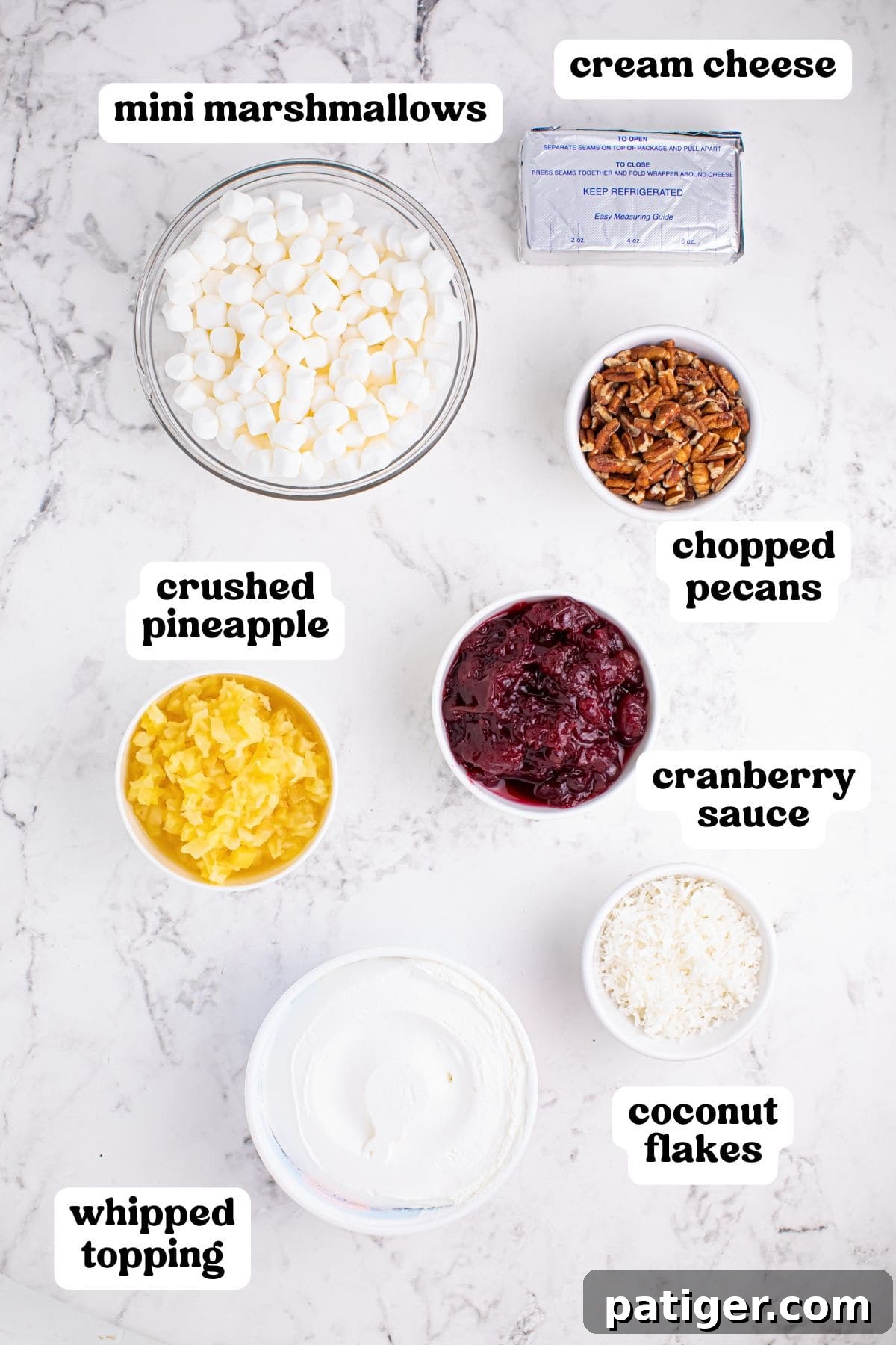 Cranberry fluff ingredients: marshmallows, pineapple, cranberry sauce, cream cheese, whipped topping, coconut, and pecans.