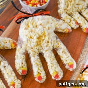 Halloween popcorn hands with candy corn as fingernails and popcorn stuffed in a plastic glove tied off with black and orange ribbon.