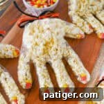 Halloween popcorn hands with candy corn as fingernails and popcorn stuffed in a plastic glove tied off with black and orange ribbon.