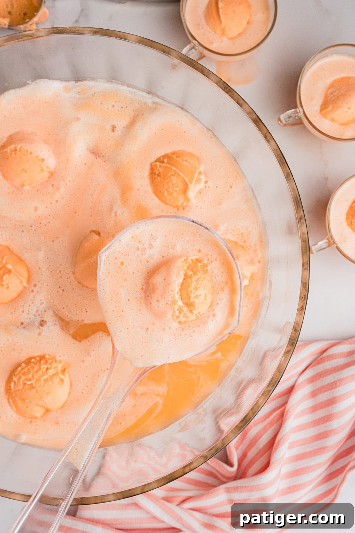 Sparkling Sherbet Punch 2 Champagne Punch with Sherbet in large glass punch bowl with glasses of punch next to it.
