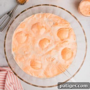 Champagne punch with orange sherbet and pineapple juice in a large glass punch bowl.