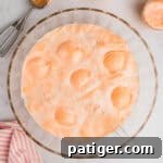 Champagne punch with orange sherbet and pineapple juice in a large glass punch bowl.