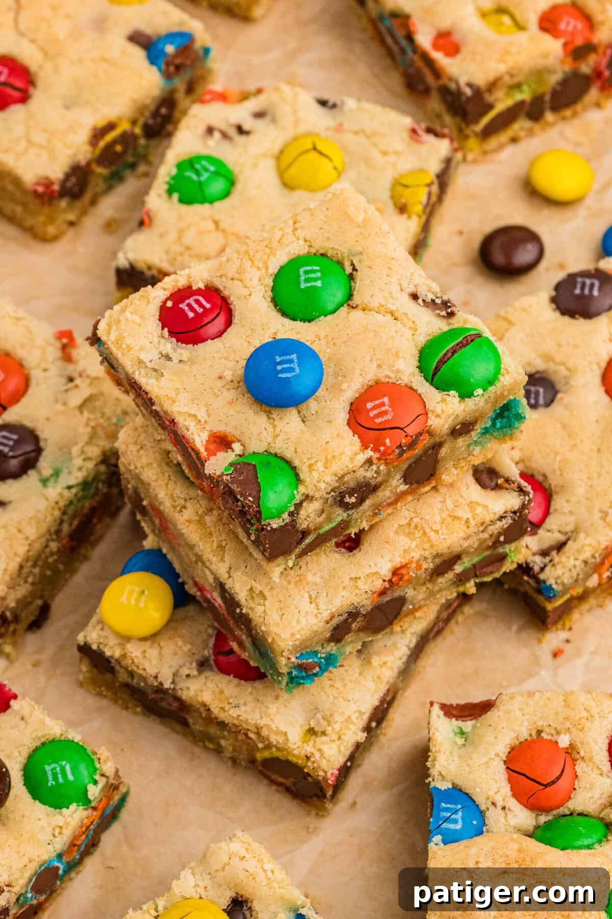 Vibrant M&M cookie bars with visible chocolate chips arranged on parchment paper, highlighting their delicious and colorful appeal, ready for enjoyment.