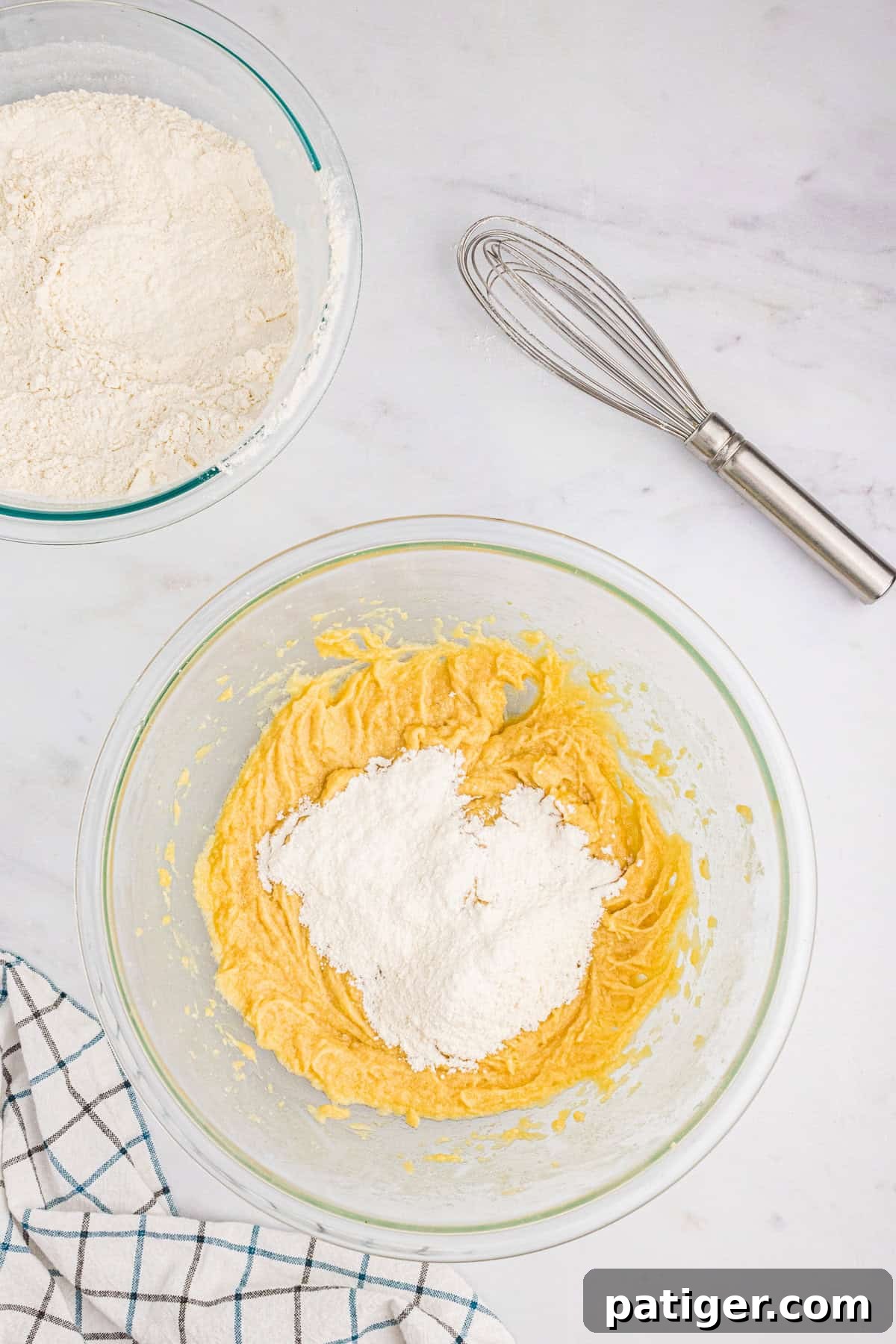 Dry ingredients (flour mixture) being gradually added to the wet ingredients in a mixing bowl, showing the careful incorporation process.