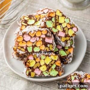 Stained glass church window cookies with bright marshmallow pieces and walnuts wrapped in a rich chocolate and coconut layer, served on a plate.
