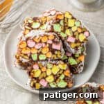 Stained glass church window cookies with bright marshmallow pieces and walnuts wrapped in a rich chocolate and coconut layer, served on a plate.