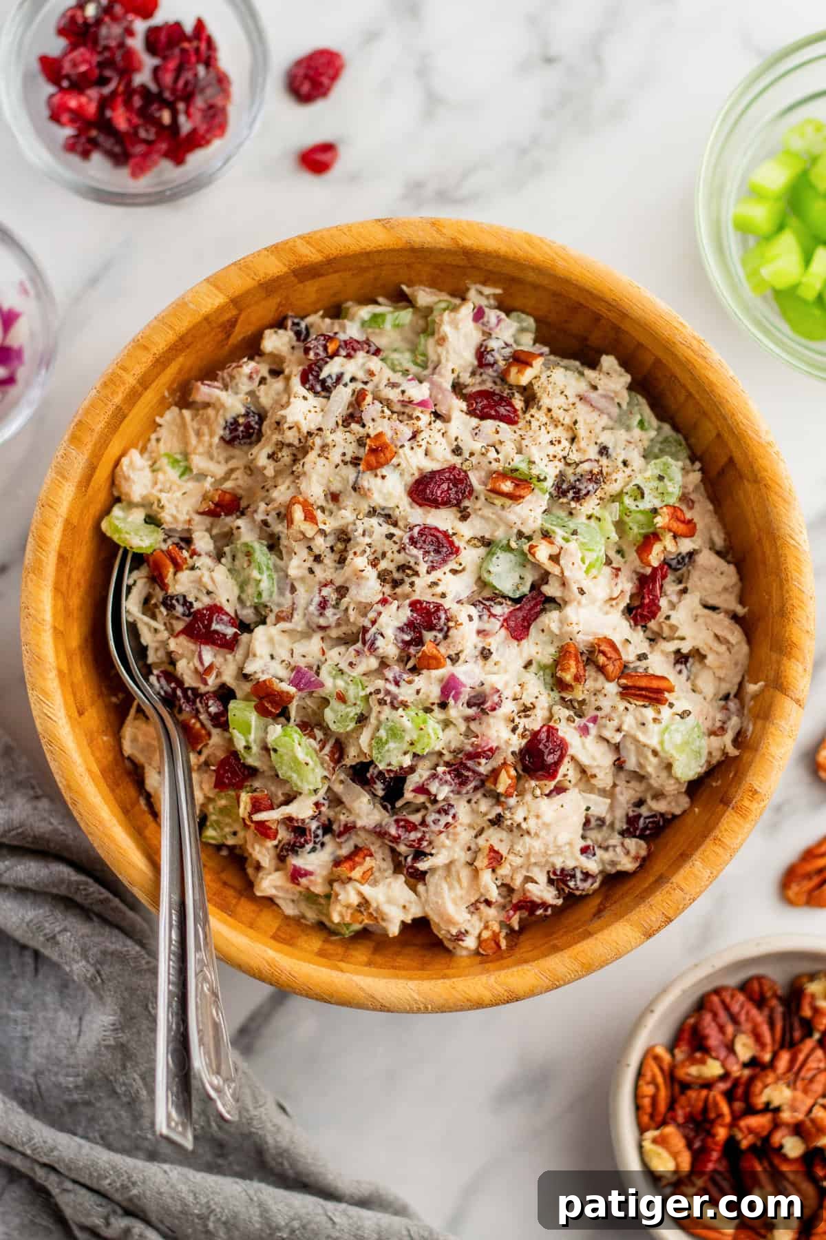 Vibrant cranberry chicken salad with pecans, celery, and red onion, tossed in a creamy dressing and served invitingly in a rustic wooden bowl.