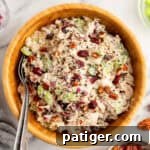 Cranberry chicken salad with pecans, celery, and red onion, in a creamy dressing served in a wooden bowl.