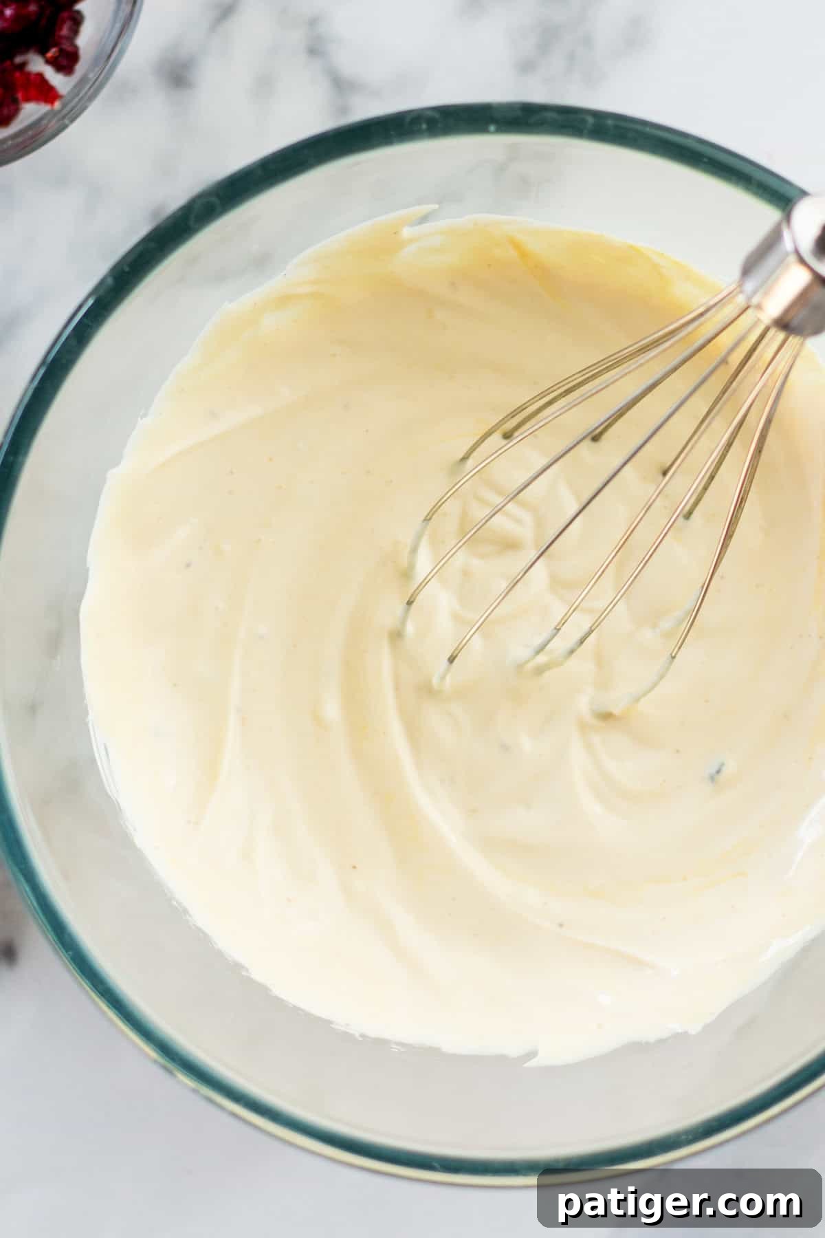 A bowl of creamy mayonnaise and sour cream-based dressing, perfectly seasoned and ready to elevate the chicken salad with its rich and zesty flavor.
