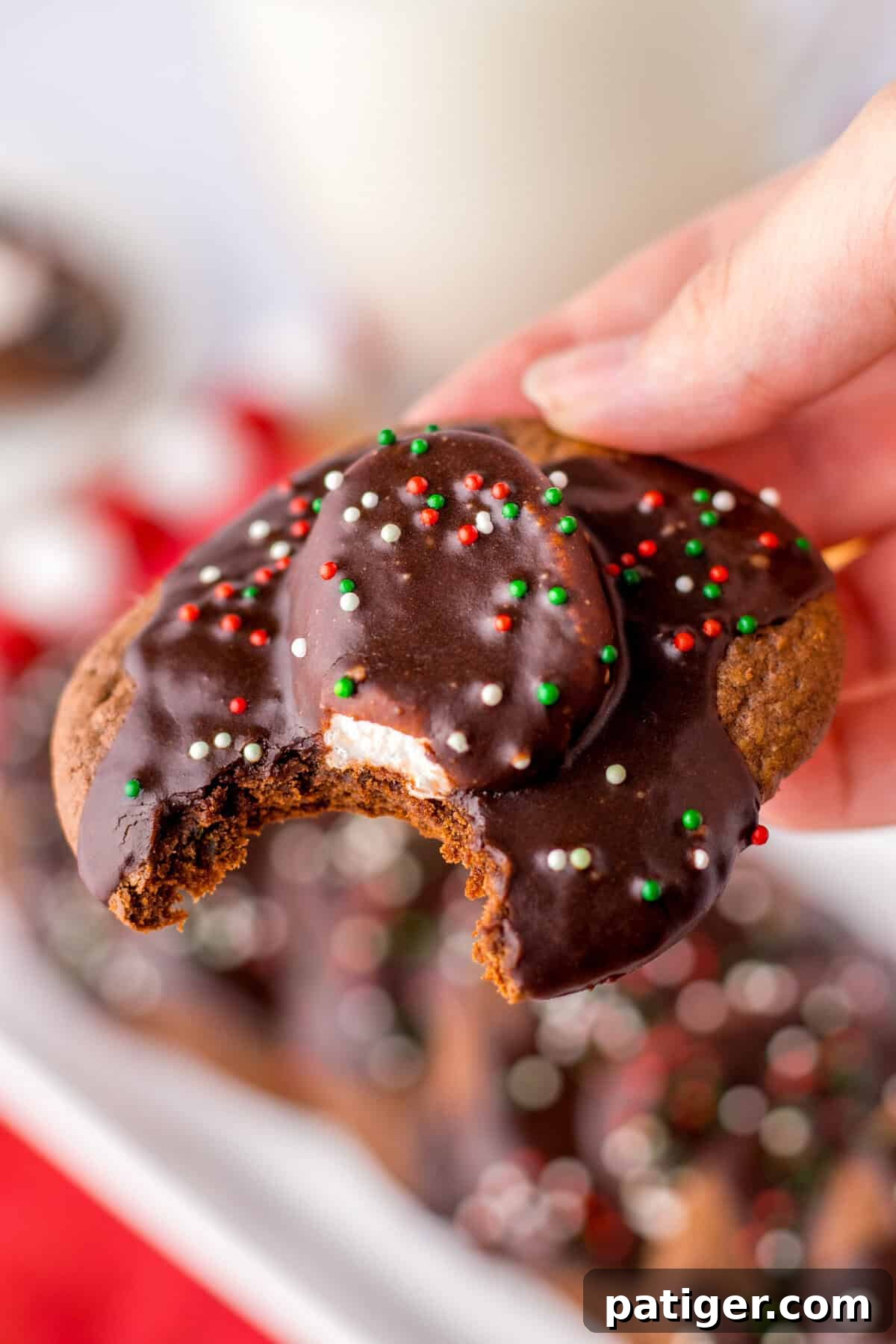 Cozy Hot Cocoa Cookies 9 Bite taken from a hot chocolate cookie topped with marshmallow, chocolate icing, and holiday sprinkles.