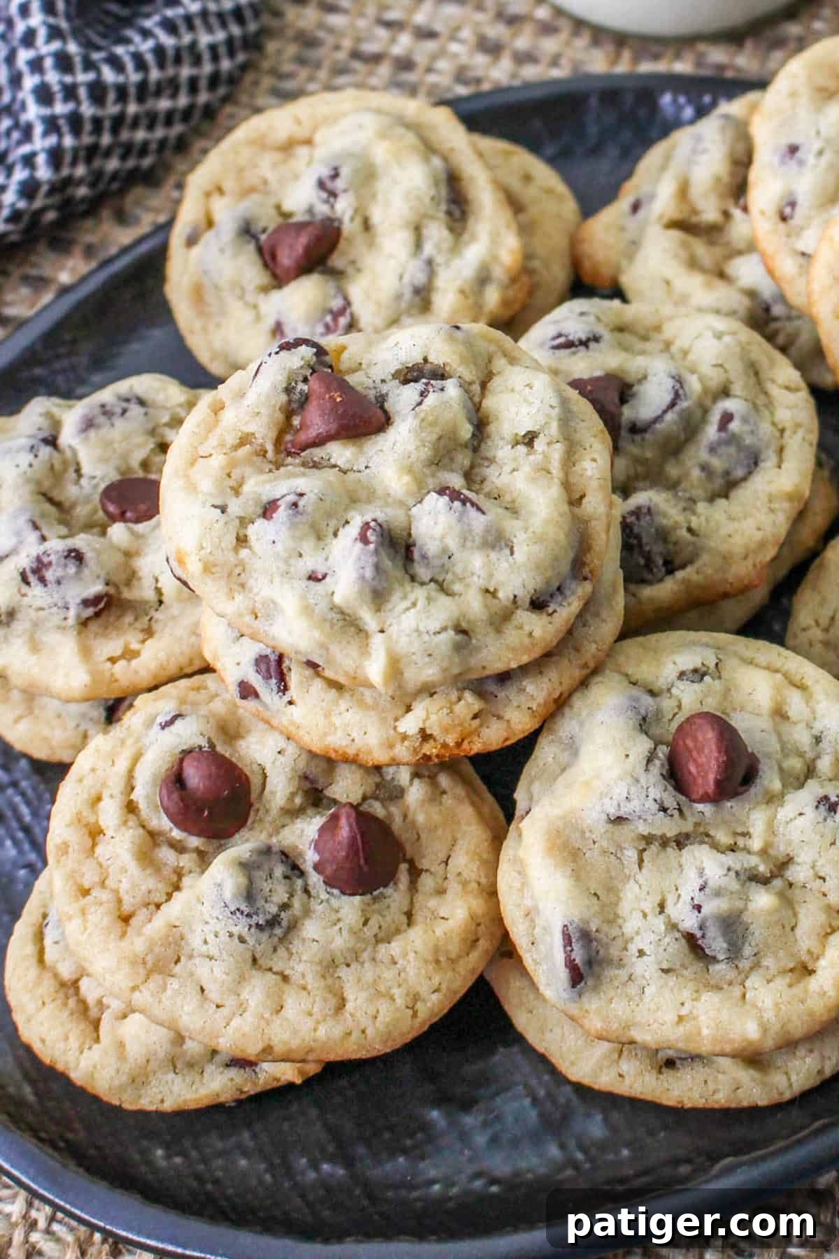 A plate full of golden-brown Greek yogurt chocolate chip cookies, adorned with melted chocolate chips, perfect for a sweet, egg-free treat. A glass of milk sits invitingly in the background.