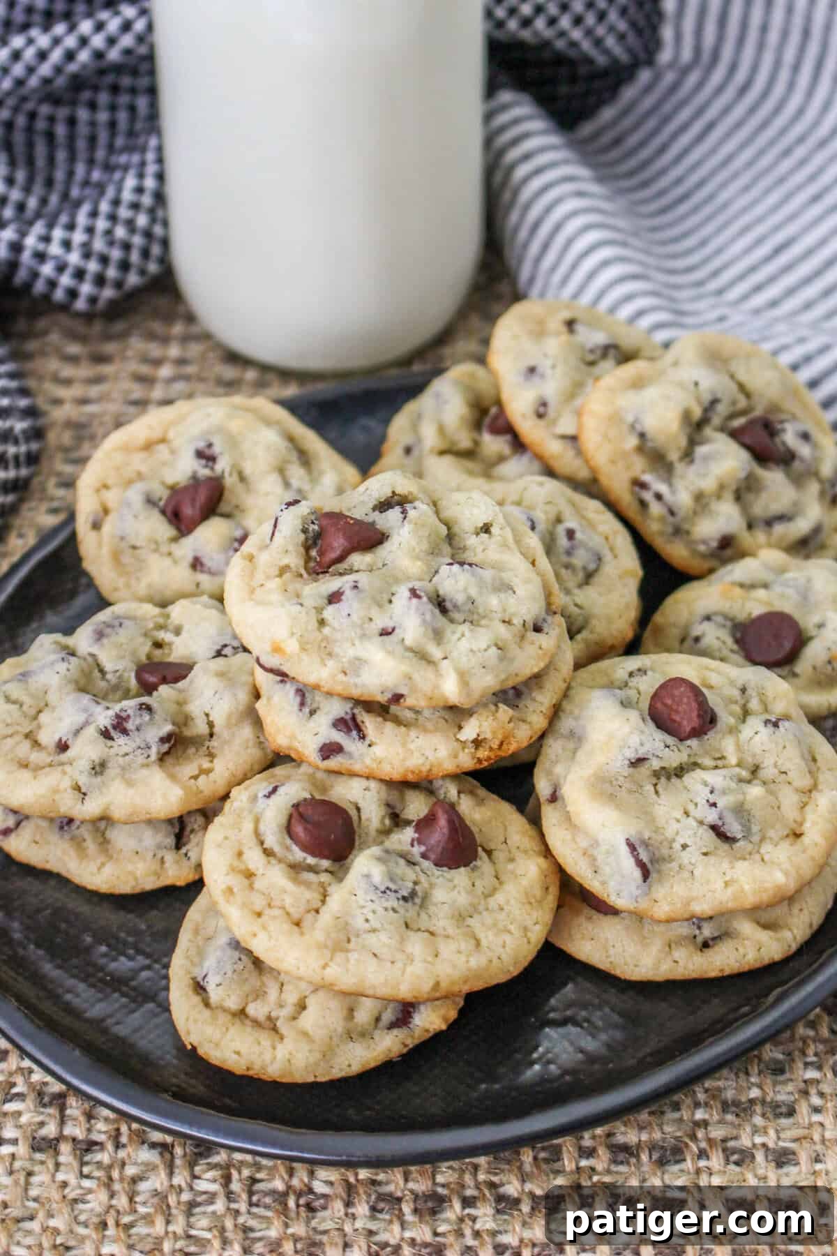 Beautifully baked Greek yogurt chocolate chip cookies arranged on a black plate, with a refreshing glass of milk in the background, ready to be enjoyed.