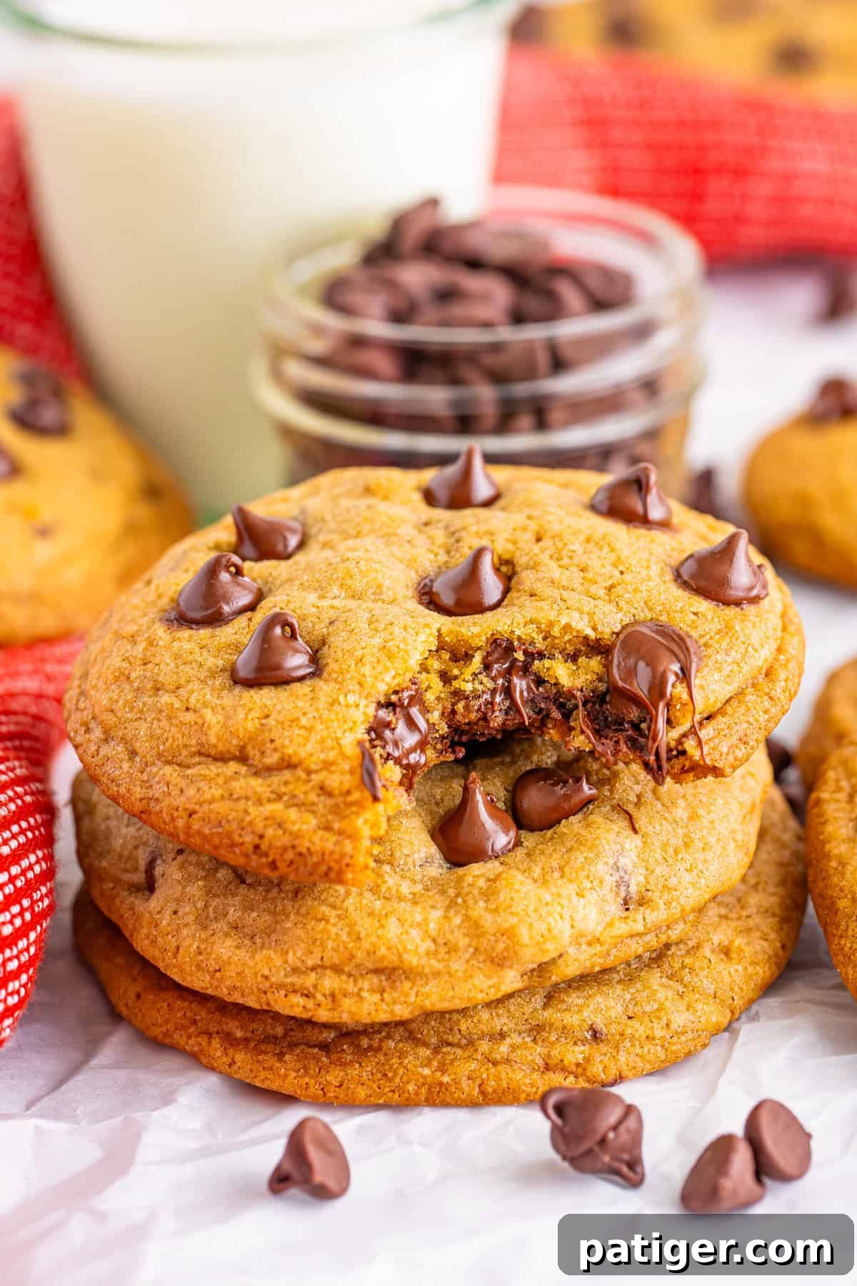 A stack of Mrs. Fields copycat chocolate chip cookies with one cookie bitten to reveal the gooey chocolate inside. This recipe shows how to make chocolate chip cookies just like Mrs. Fields.