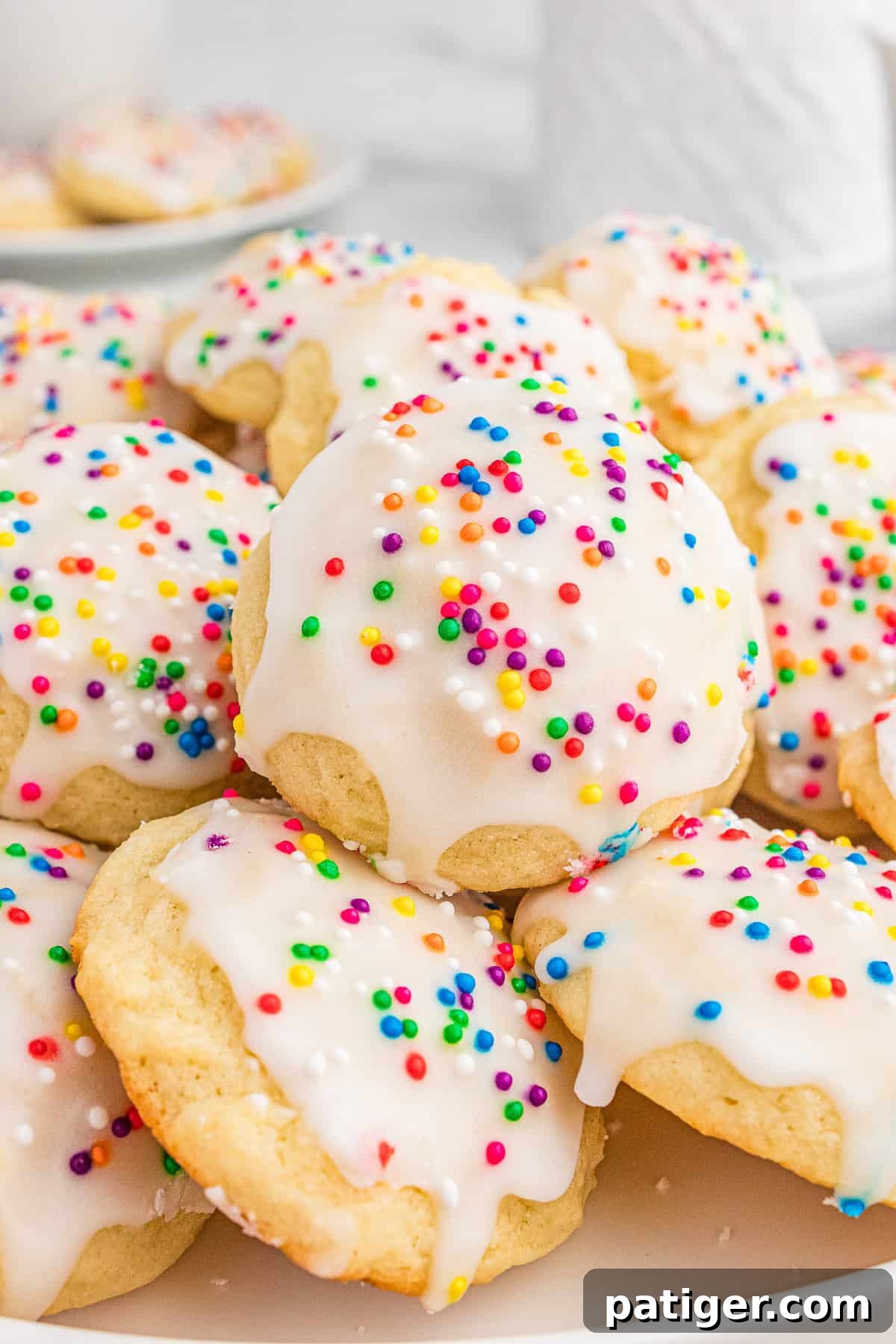 Classic Italian Ricotta Cookies 8 A close-up of Italian ricotta cookies topped with glossy white icing and colorful sprinkles, stacked on a plate. The soft texture of the cookies and the vibrant sprinkles create a festive and inviting presentation.