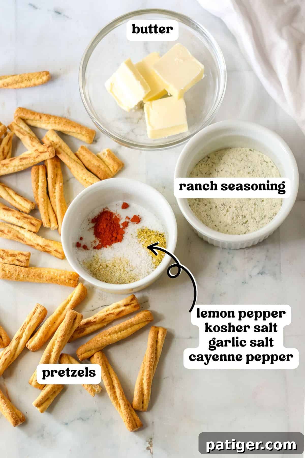 Assortment of ingredients for seasoned pretzels, including melted butter, dry ranch seasoning packet, lemon pepper, kosher salt, garlic salt, and cayenne pepper, beautifully arranged around a pile of pretzel sticks on a wooden surface.