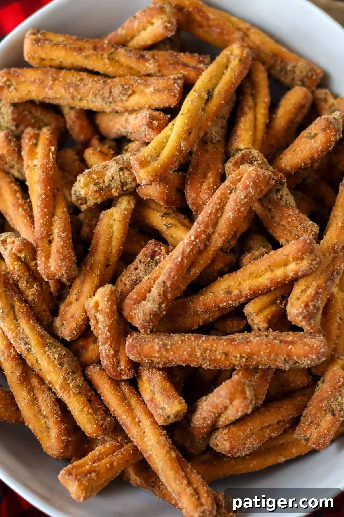 A tightly cropped view of delicious golden-brown seasoned pretzel sticks presented in a simple white bowl, showcasing their irresistible texture and perfectly applied spice coating, reminiscent of Dot's pretzel seasoning mix.