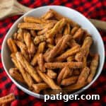 A bowl of seasoned pretzel sticks, similar to Dot's pretzels, on a red plaid background.