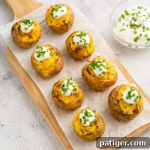Bite-sized mini loaded potatoes arranged on a wooden serving board as an appetizer.