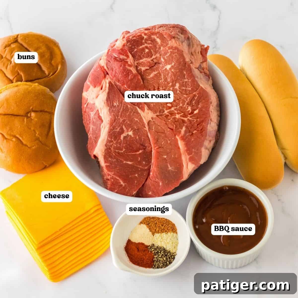 Melt-in-Your-Mouth Slow Cooker BBQ Beef 4 Overhead image showing labeled ingredients for a slow cooker BBQ beef recipe. A bowl of raw chuck roast is in the center. Surrounding it are hamburger buns, sub rolls, a stack of cheddar cheese slices, a small bowl of mixed seasonings, and a ramekin of BBQ sauce.