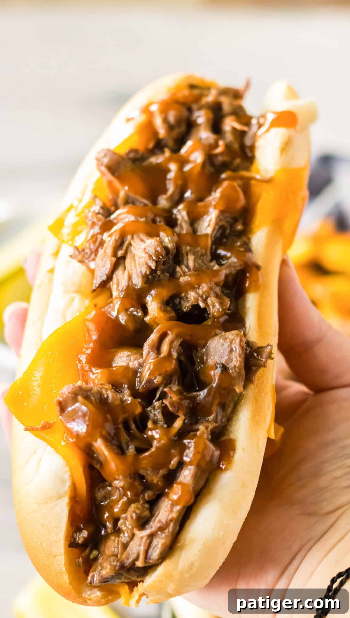 Melt-in-Your-Mouth Slow Cooker BBQ Beef 8 Hand holds a shredded BBQ beef sandwich.