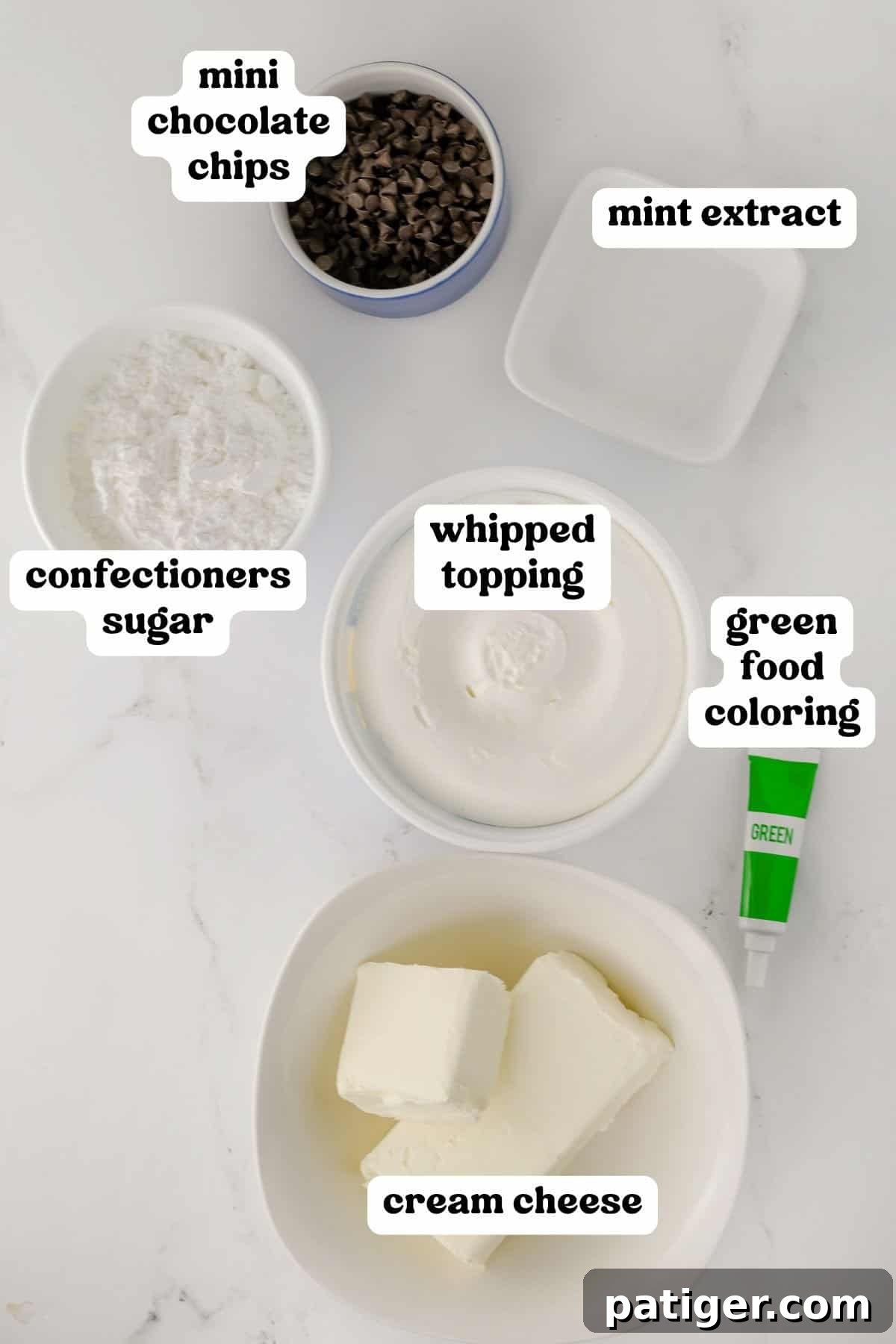 Ingredients for mint chocolate chip dip, including cream cheese, whipped topping, sugar, mint extract, green food coloring, and mini chocolate chips.