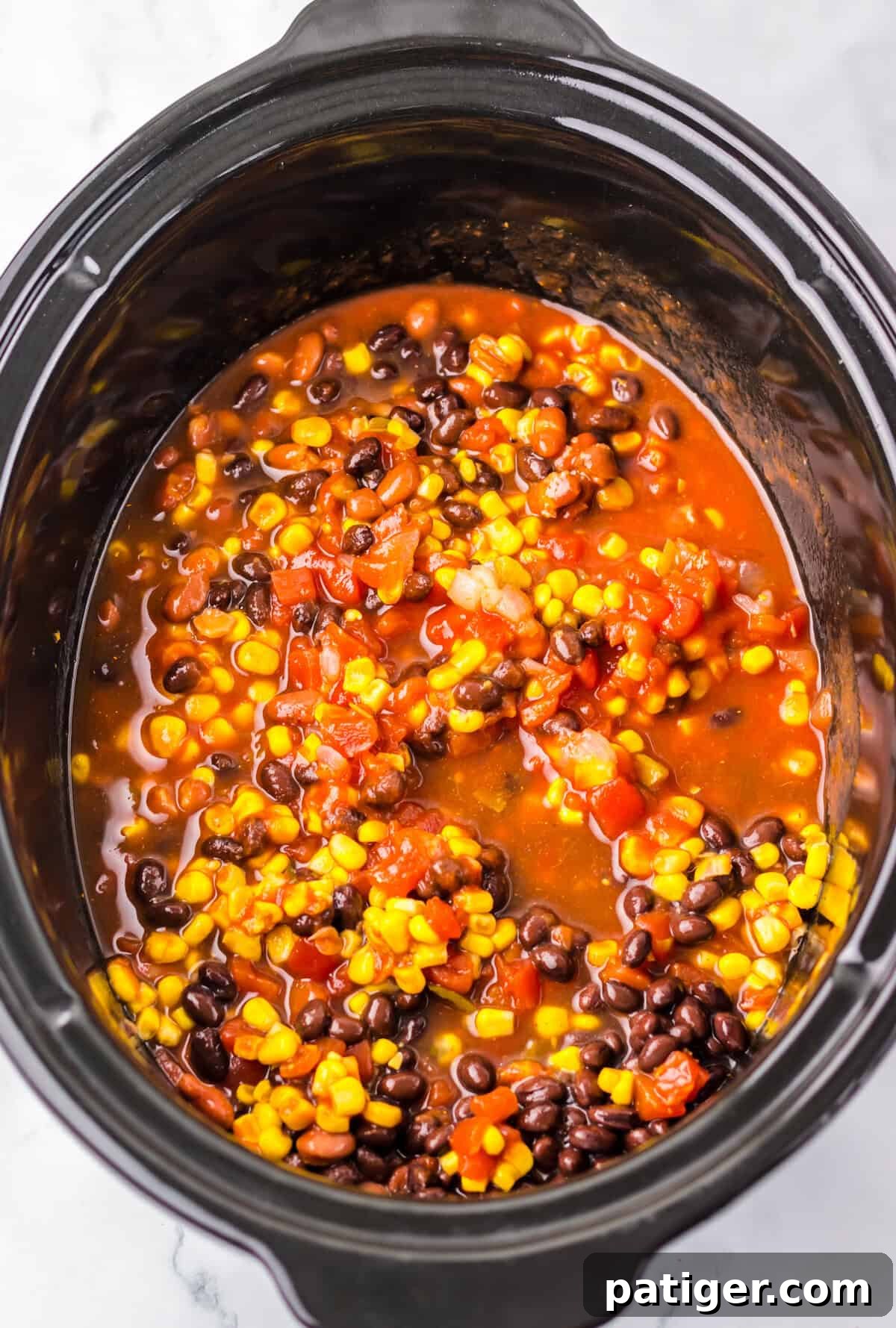 Ingredients for easy slow cooker chicken taco soup cooking in a crockpot.