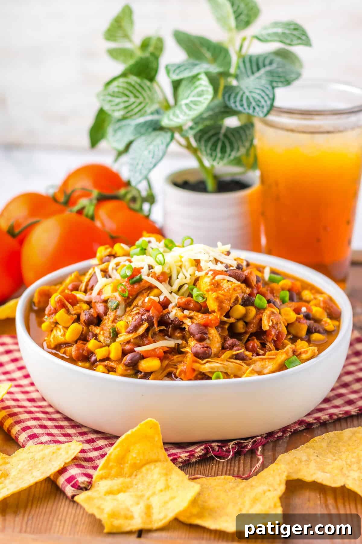 A bowl of crockpot chicken taco soup garnished with cheese and green onions, served with tortilla chips.