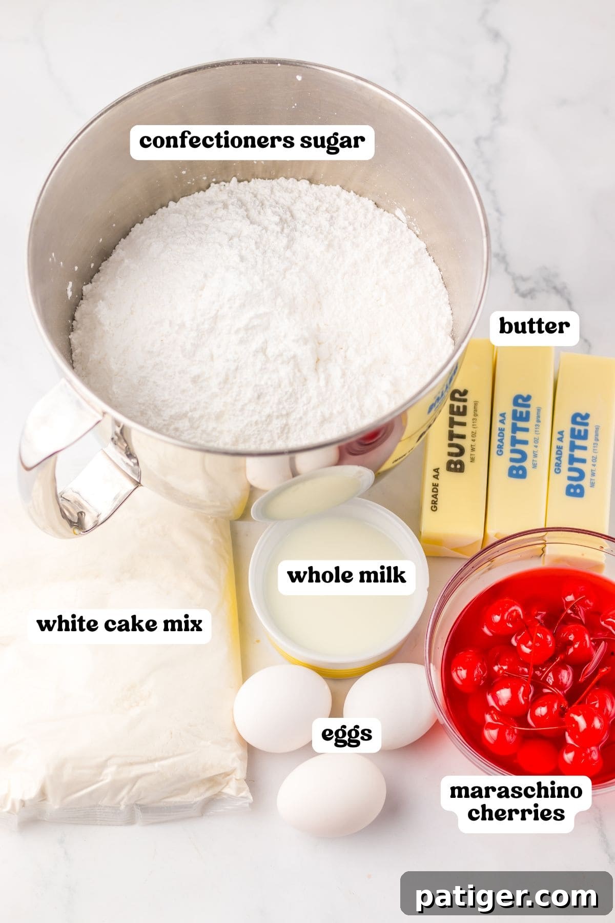 An overhead view showcasing the labeled ingredients required for baking a maraschino cherry cake. Components include a shimmering metal bowl filled with confectioners' sugar, neat sticks of unsalted butter, a package of classic white cake mix, a small bowl of fresh whole milk, three brown eggs, and a glass bowl brimming with bright red maraschino cherries immersed in their sweet syrup.