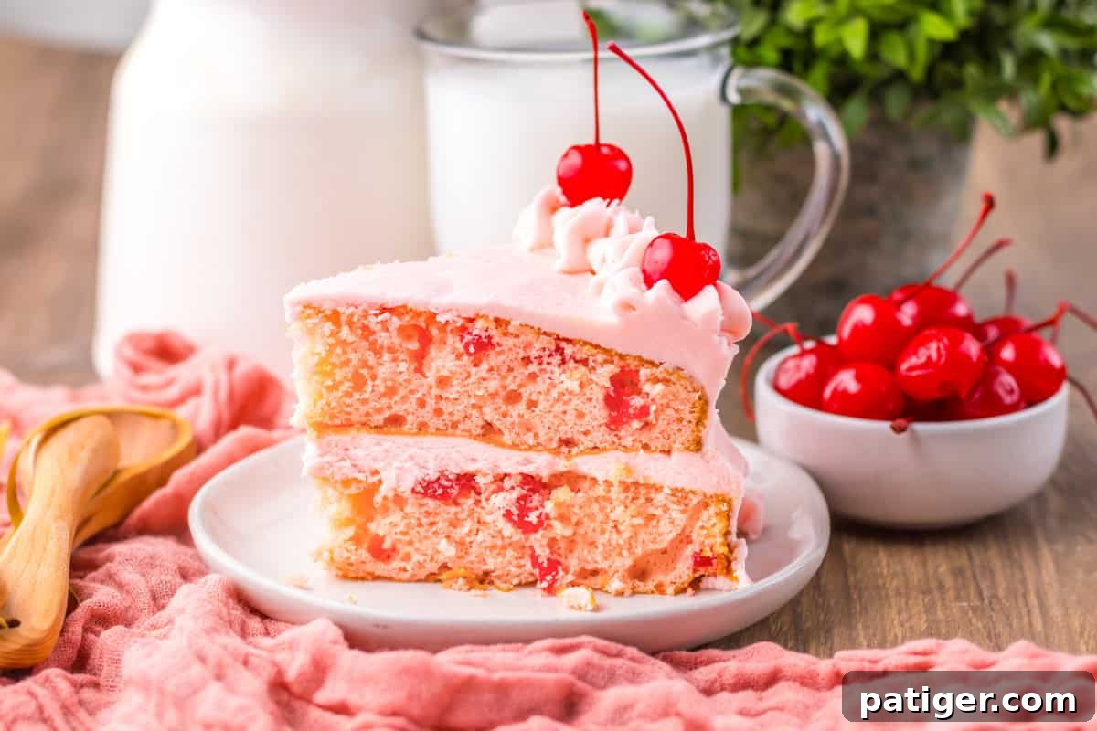 A delectable side view of a slice of maraschino cherry cake, showcasing its beautifully moist, pale pink layers studded with vibrant red cherry pieces. The slice is generously filled and covered with smooth pink frosting and crowned with a fresh maraschino cherry, highlighting its irresistible texture and flavor.