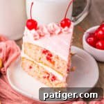 Close-up of a slice of cherry chip cake with pink frosting and cherries.