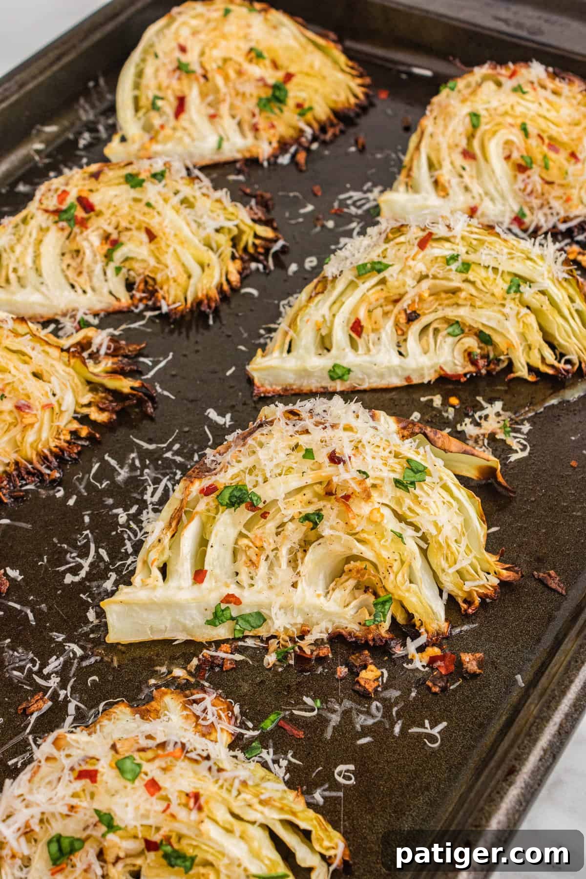 Caramelized Cabbage Bites 3 Fresh garlic parmesan roasted cabbage wedges laid out on a baking sheet, ready for the oven to caramelize and crisp them to perfection.