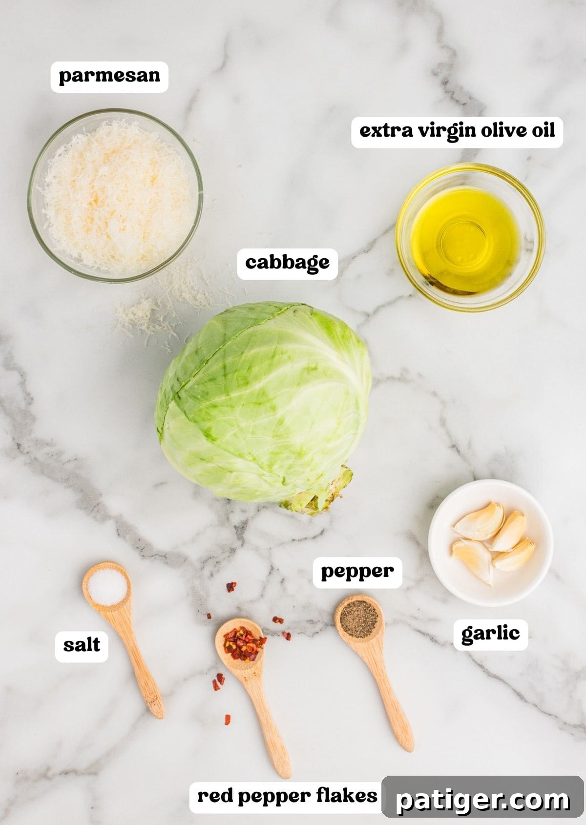 Caramelized Cabbage Bites 4 A vibrant display of ingredients for roasted cabbage wedges on a clean countertop, featuring a fresh head of green cabbage, glistening extra virgin olive oil, freshly grated Parmesan cheese, a scattering of salt, pepper, and fiery red pepper flakes, alongside four cloves of aromatic garlic.