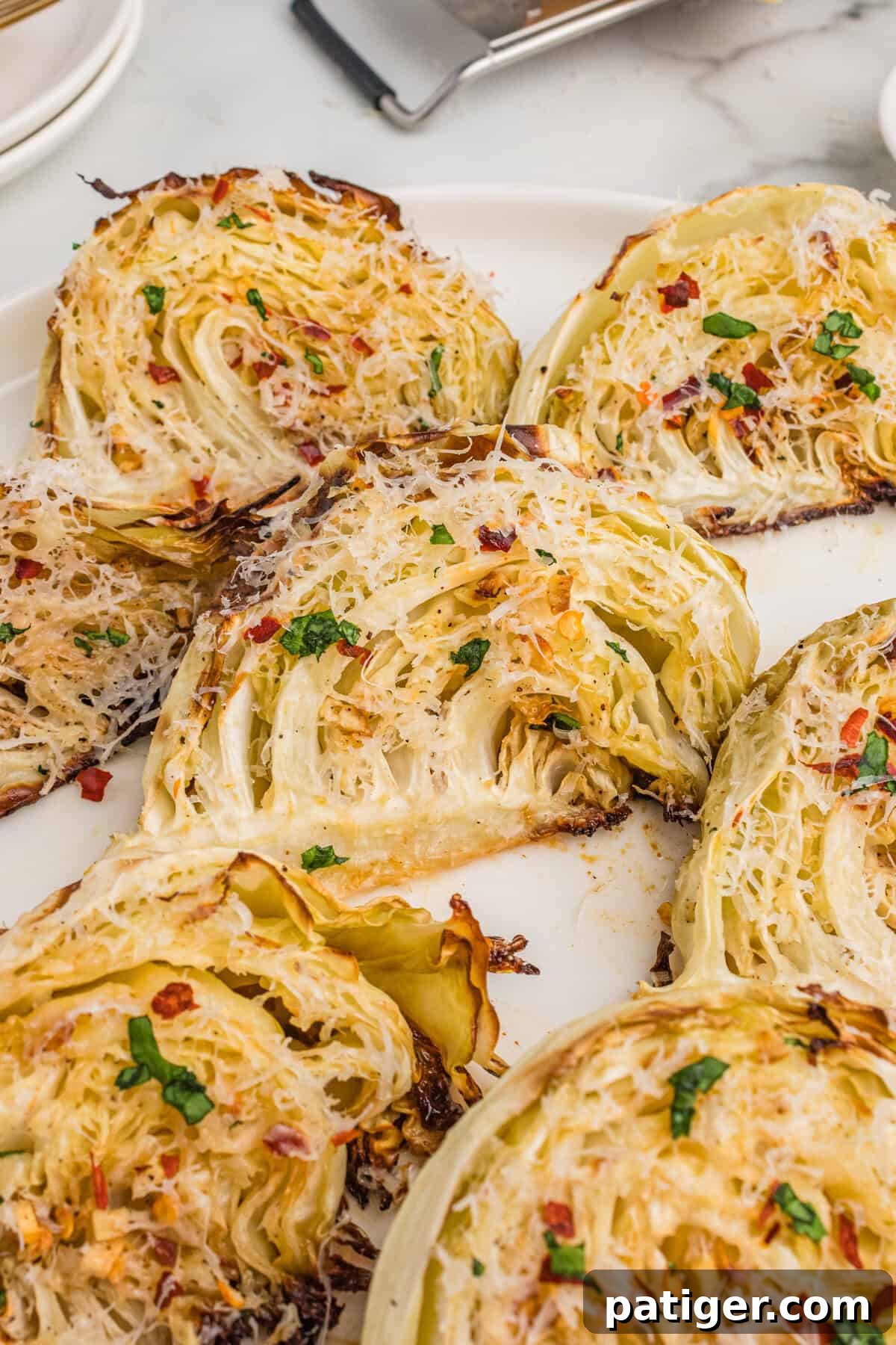 Caramelized Cabbage Bites 8 An inviting overhead view of golden-brown roasted cabbage wedges, beautifully seasoned with aromatic garlic, grated Parmesan cheese, and a sprinkle of vibrant red pepper flakes, ready to be enjoyed.