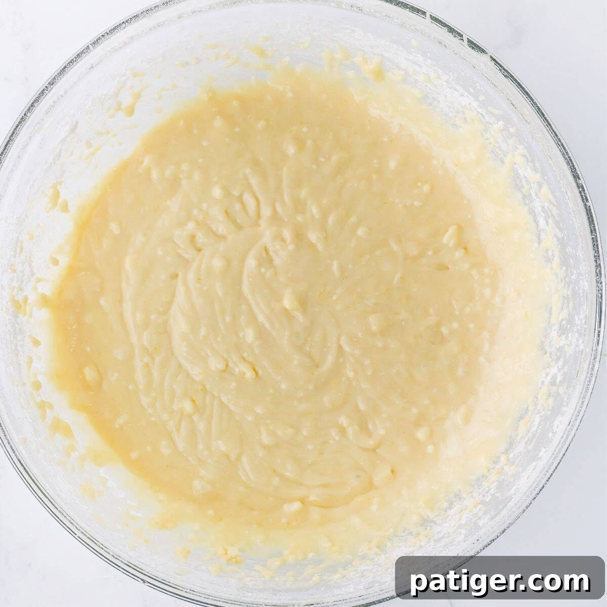 Scrumptious Strawberry Crumb Cake 5 A close-up shot of a glass mixing bowl filled with a smooth, pale yellow cake batter, showcasing its creamy consistency before being spread into a baking dish.