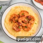Loaded Cheesy Shrimp Grits 13 A bowl of cheesy shrimp and grits garnished with green onions and bacon.