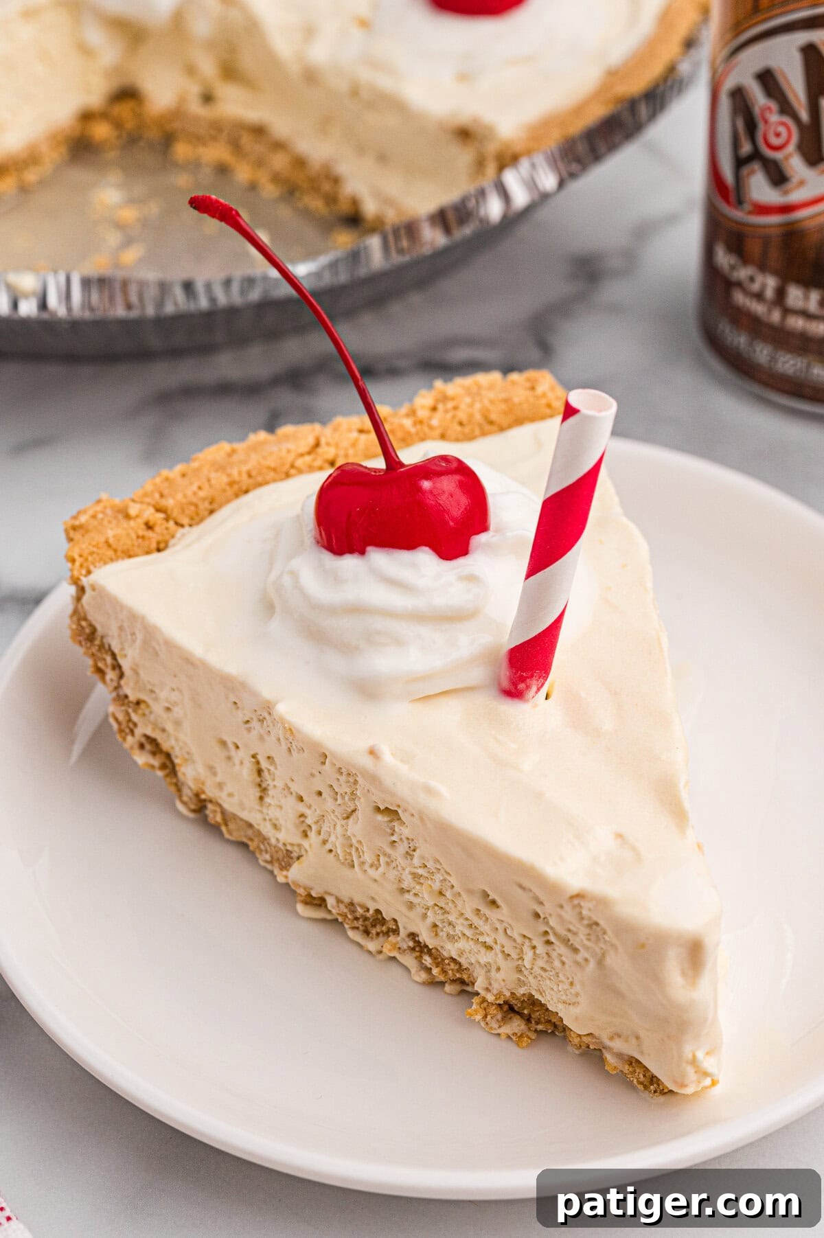 A slice of root beer float pie on a white plate, topped with whipped cream, a cherry, and a red-striped paper straw.