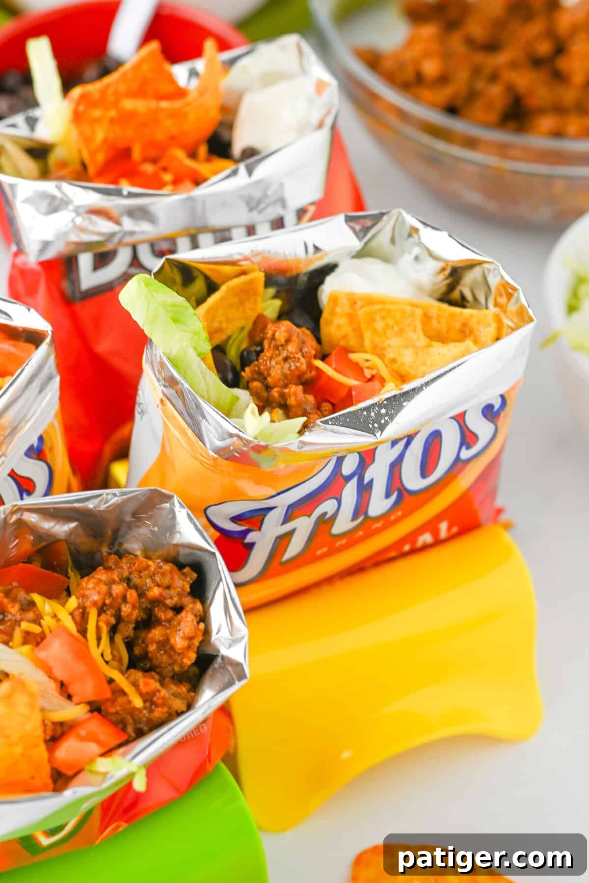 A vibrant Fritos walking taco, brimming with seasoned ground beef, shredded cheese, black beans, crisp lettuce, and a dollop of sour cream, ready to be enjoyed.