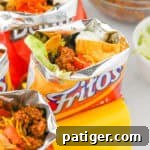 Fritos walking tacos with toppings like shredded cheese, beans, sour cream, and lettuce.