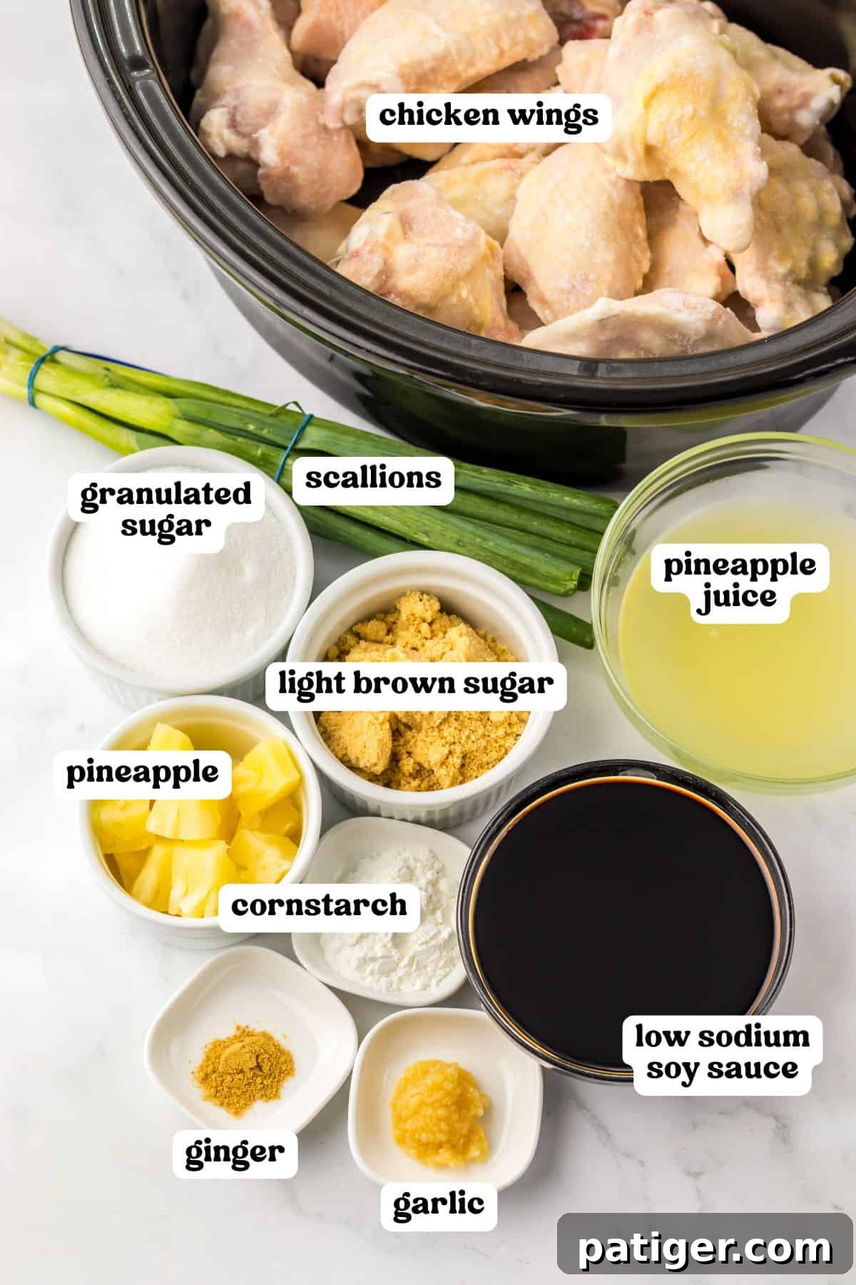 Overhead view of labeled ingredients for Hawaiian chicken wings: raw wings in a crockpot, fresh scallions, granulated sugar, rich light brown sugar, vibrant pineapple chunks, cornstarch, sweet pineapple juice, savory soy sauce, minced garlic, and aromatic ground ginger. All essentials for a flavorful dish.