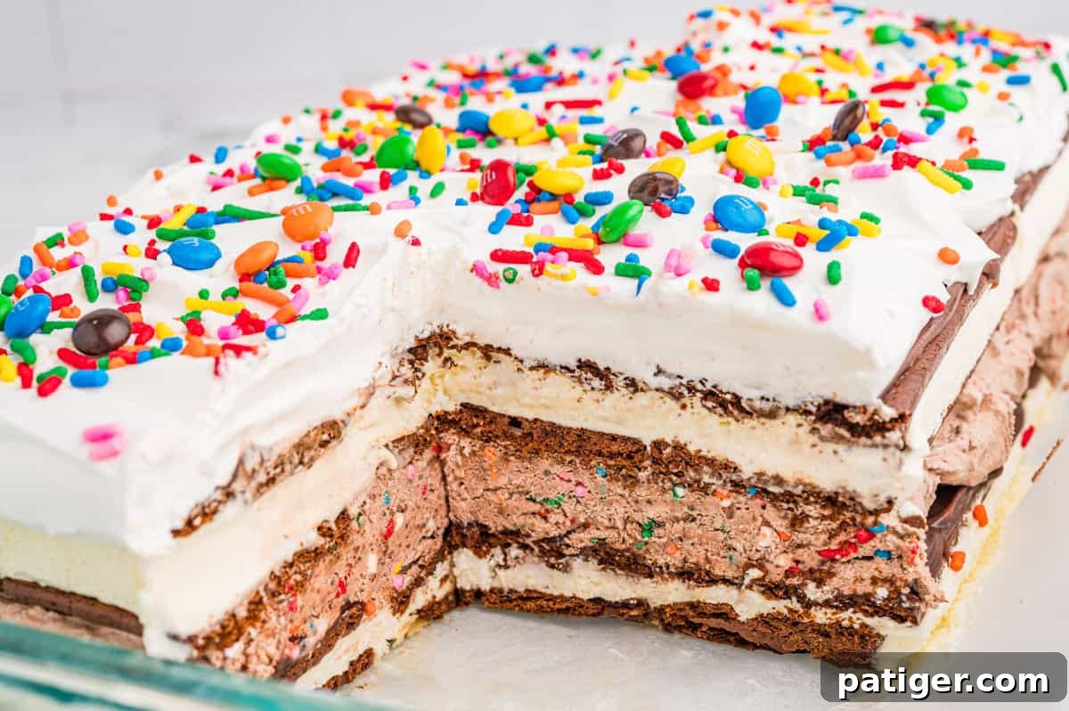 A layered ice cream sandwich cake topped with cool whip and rainbow sprinkles.