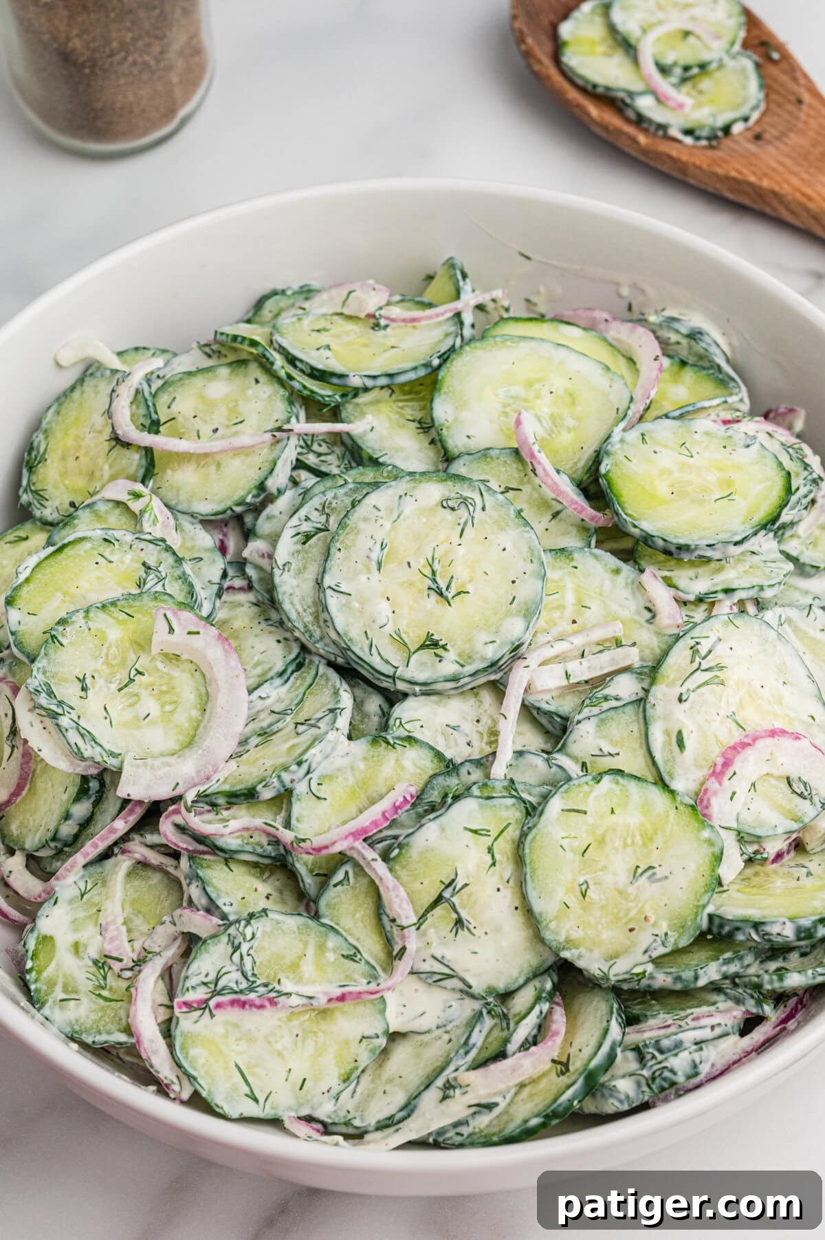 Bowl of creamy cucumber dill salad, made with sliced cucumbers, red onion, and fresh dill in a creamy dressing