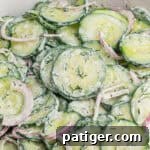 Creamy cucumber dill salad with thin cucumber slices, red onion, and chopped dill in a creamy white dressing.