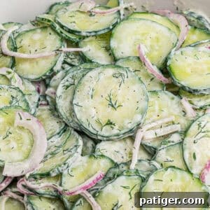 Creamy cucumber dill salad with thin cucumber slices, red onion, and chopped dill in a creamy white dressing.