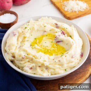 Bowl of red skin mashed potatoes with butter and herbs.
