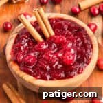 Homemade cranberry sauce in a wooden bowl with whole cranberries cinnamon sticks.
