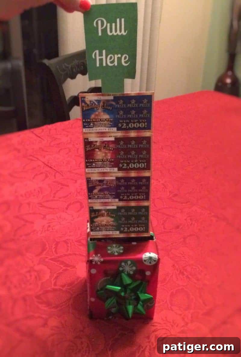 Roll of lottery ticket scratch offs attached to a "pull here" tag, being pulled out of a festive gift box.