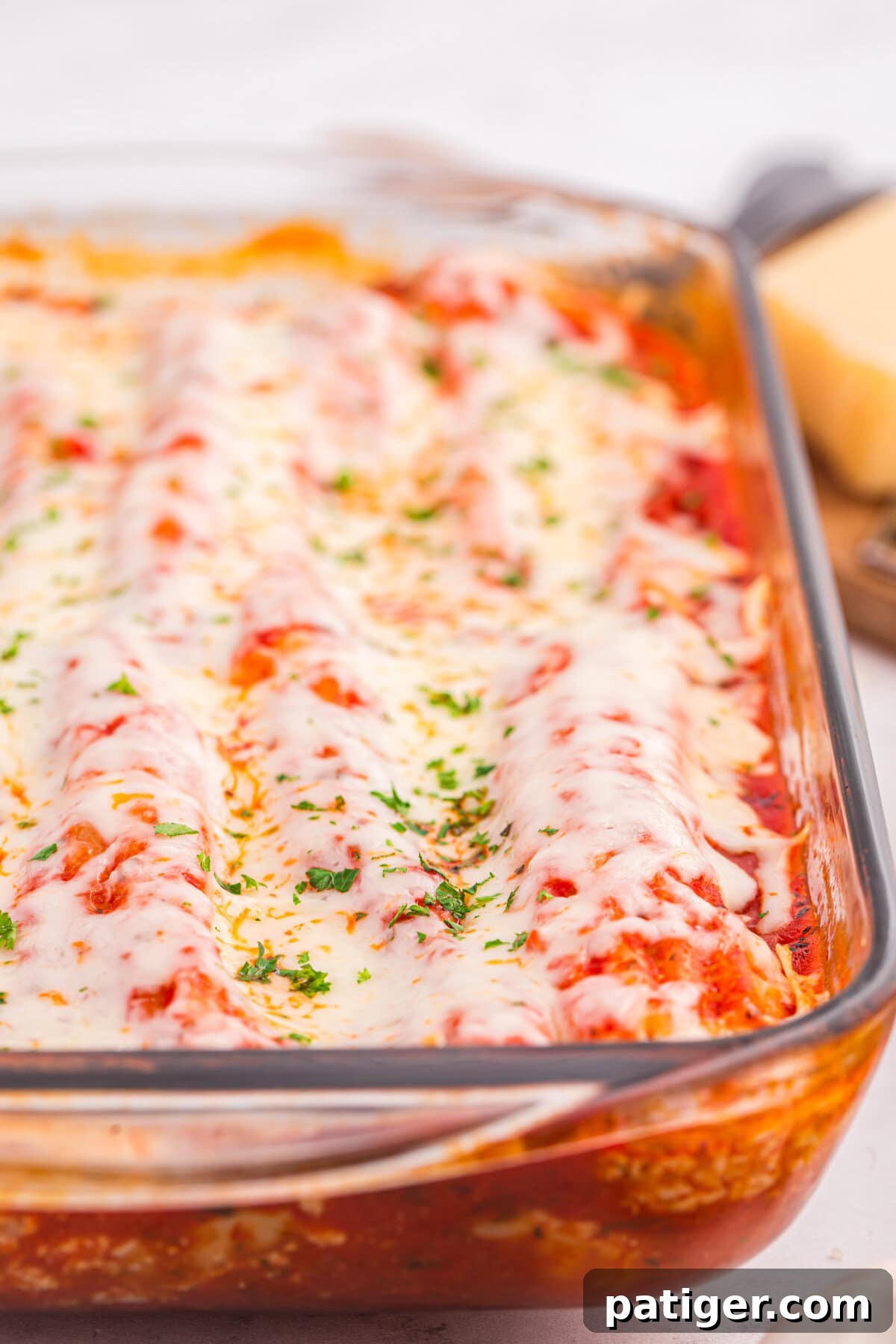 Close-up of cheesy baked manicotti in a glass dish.