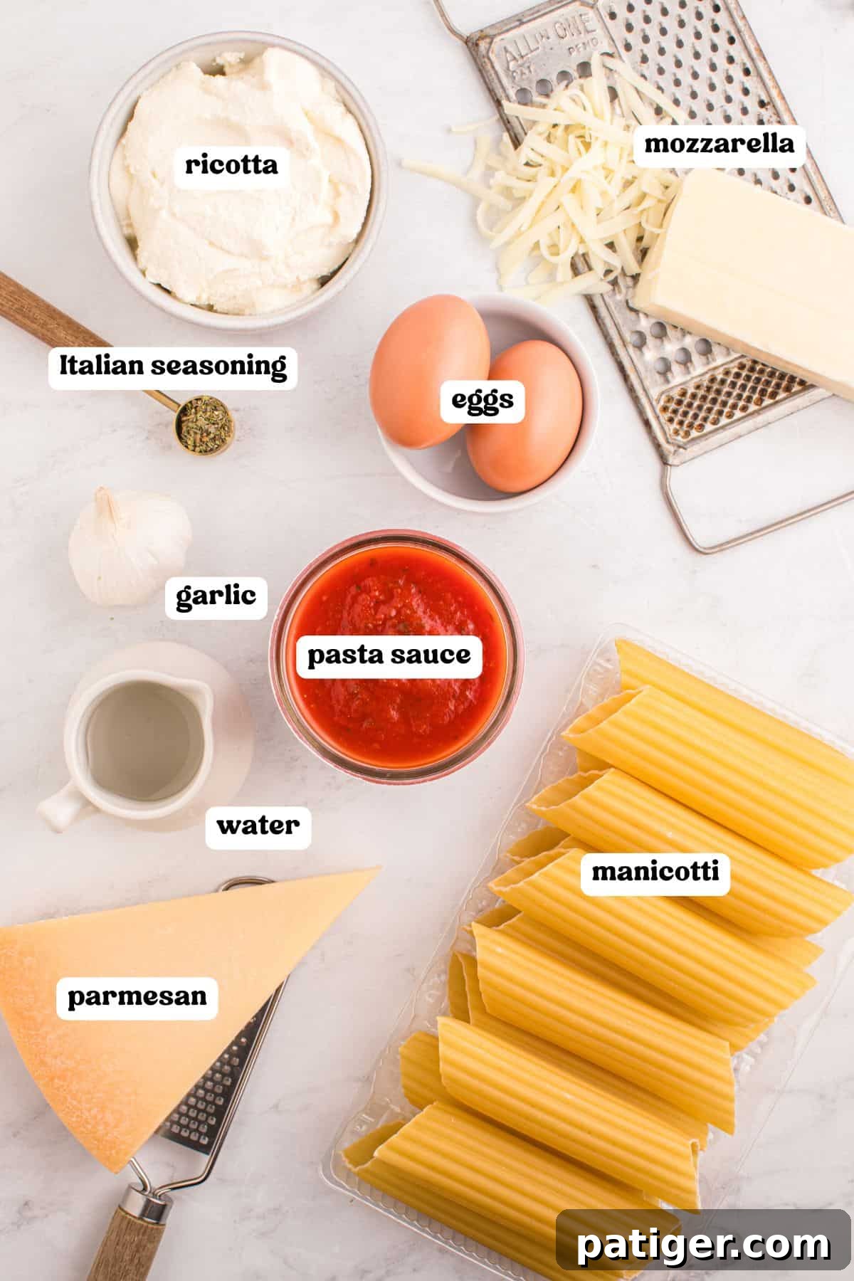 Overhead image showing ingredients for baked manicotti, each labeled: ricotta in a bowl, shredded mozzarella on a grater, eggs in a small bowl, Italian seasoning in a spoon, garlic, pasta sauce in a glass bowl, a small pitcher of water, a wedge of parmesan with a grater, and uncooked manicotti in a plastic tray.