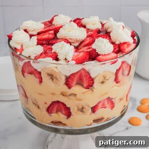 Strawberry banana pudding layered with fruit, pudding, and whipped cream in a trifle dish.